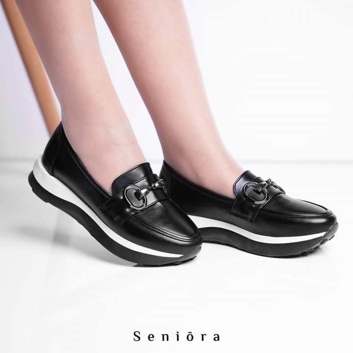 Mocassin noir avec une touche du blanc orné d'un accessoire métallique 