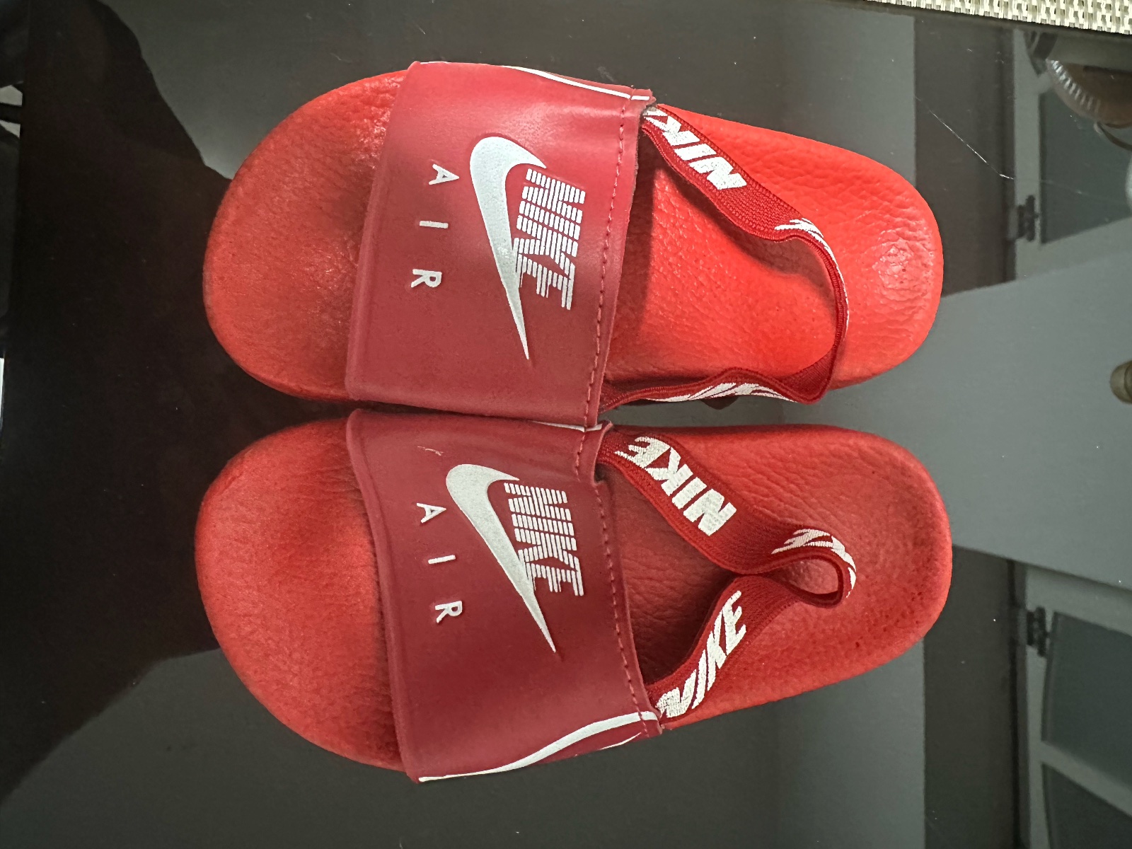 Ces claquettes rouges Nike Air sont des sandales décontractées dotées d'une large bande confortable sur le dessus