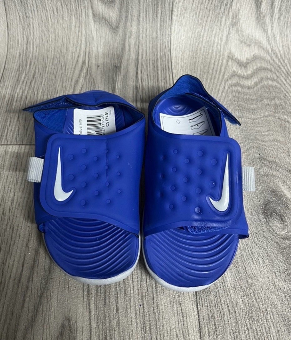 Ces sandales pour enfants sont des Nike Sunray Adjust de couleur bleue avec le logo Nike argenté