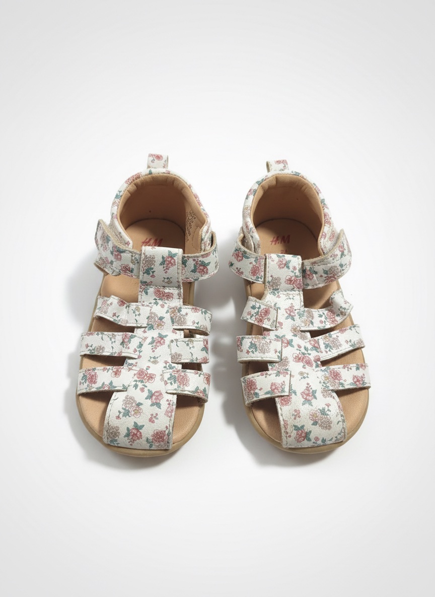 Ces sandales H&M blanches présentent un motif floral rose et vert et se ferment avec une bande auto-agrippante