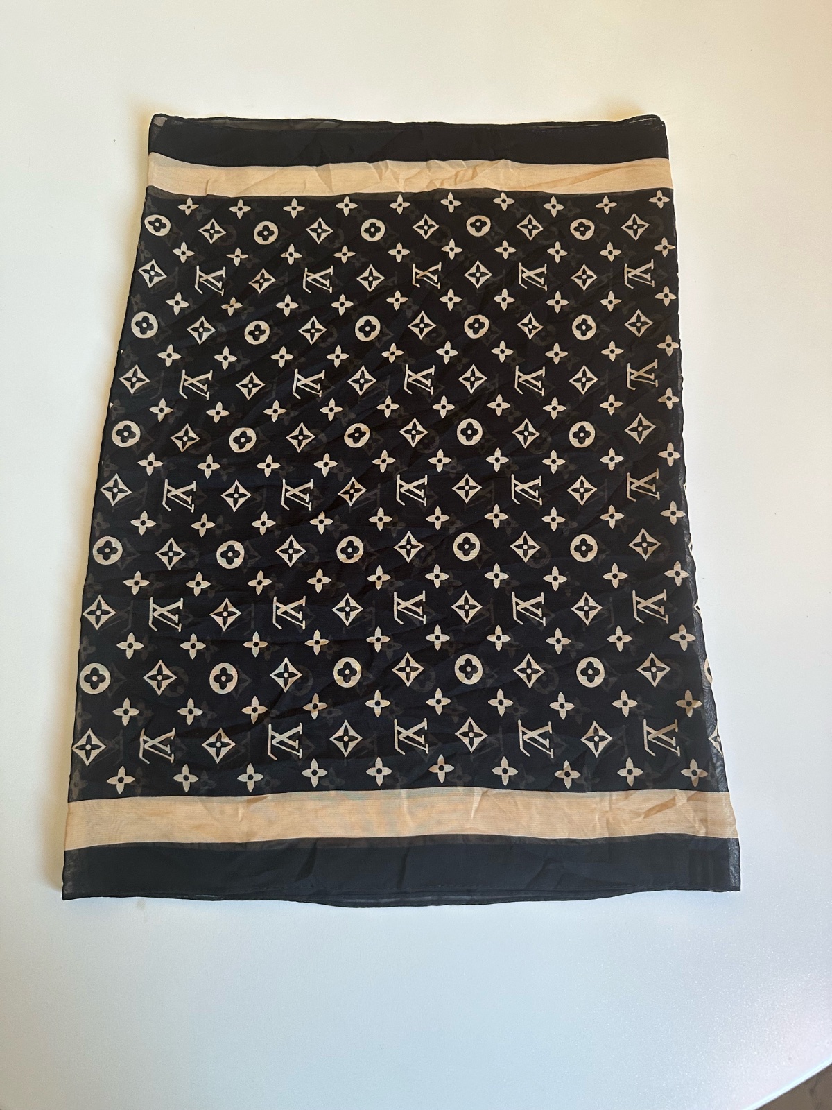 Cette étole Louis Vuitton présente un motif Monogram classique en beige sur un fond noir