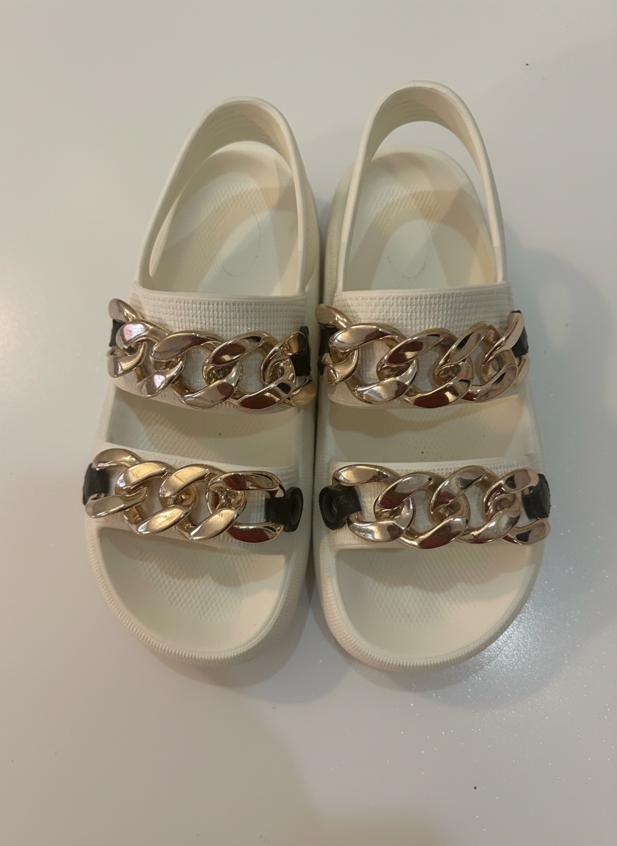 Ces sandales blanches Kenneth Cole "Mello Eva" sont ornées de chaînes dorées imposantes.