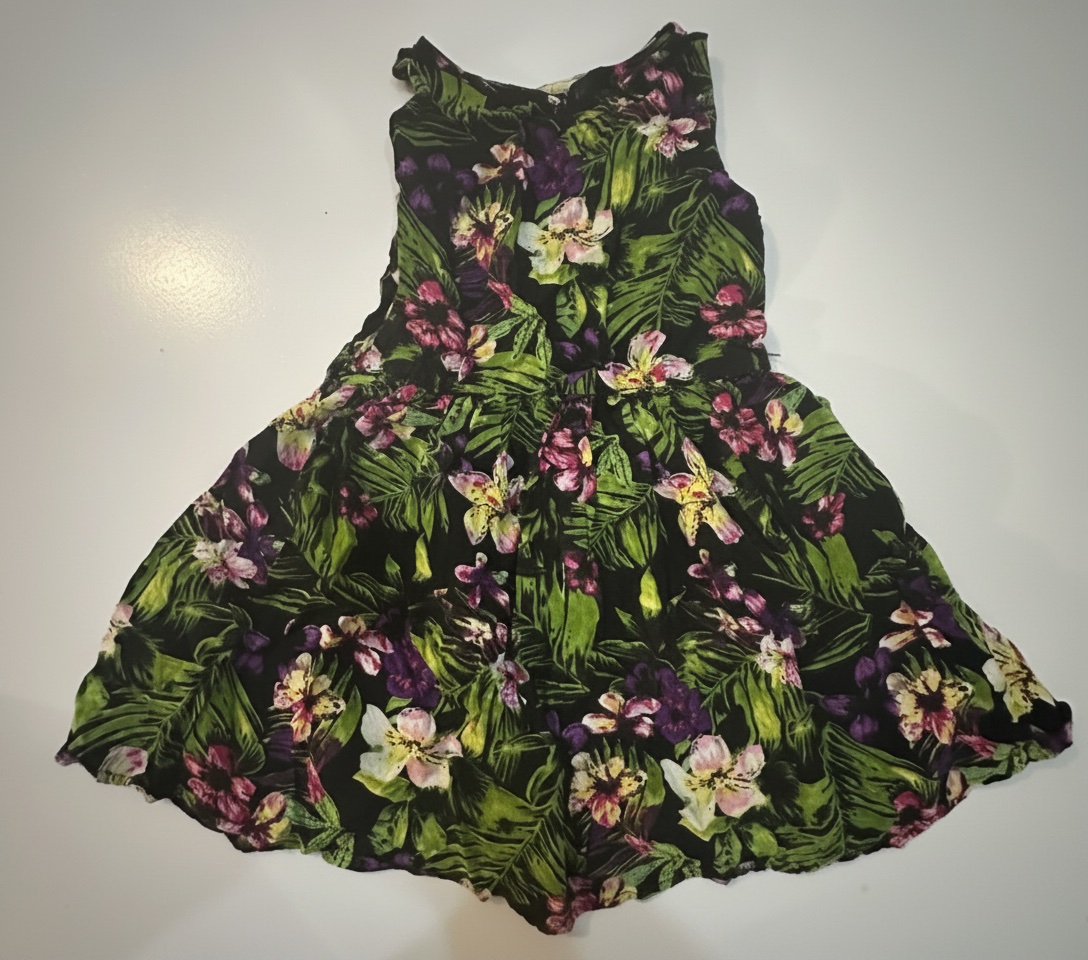 Cette robe Roxy Playa Baby présente un imprimé tropical éclatant sur un fond noir avec un corsage froncé et des bretelles réglables