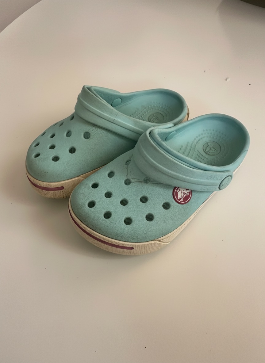 Ces sabots Crocs Crocband II pour enfants sont de couleur bleu glace avec une bande rose bonbon distinctive