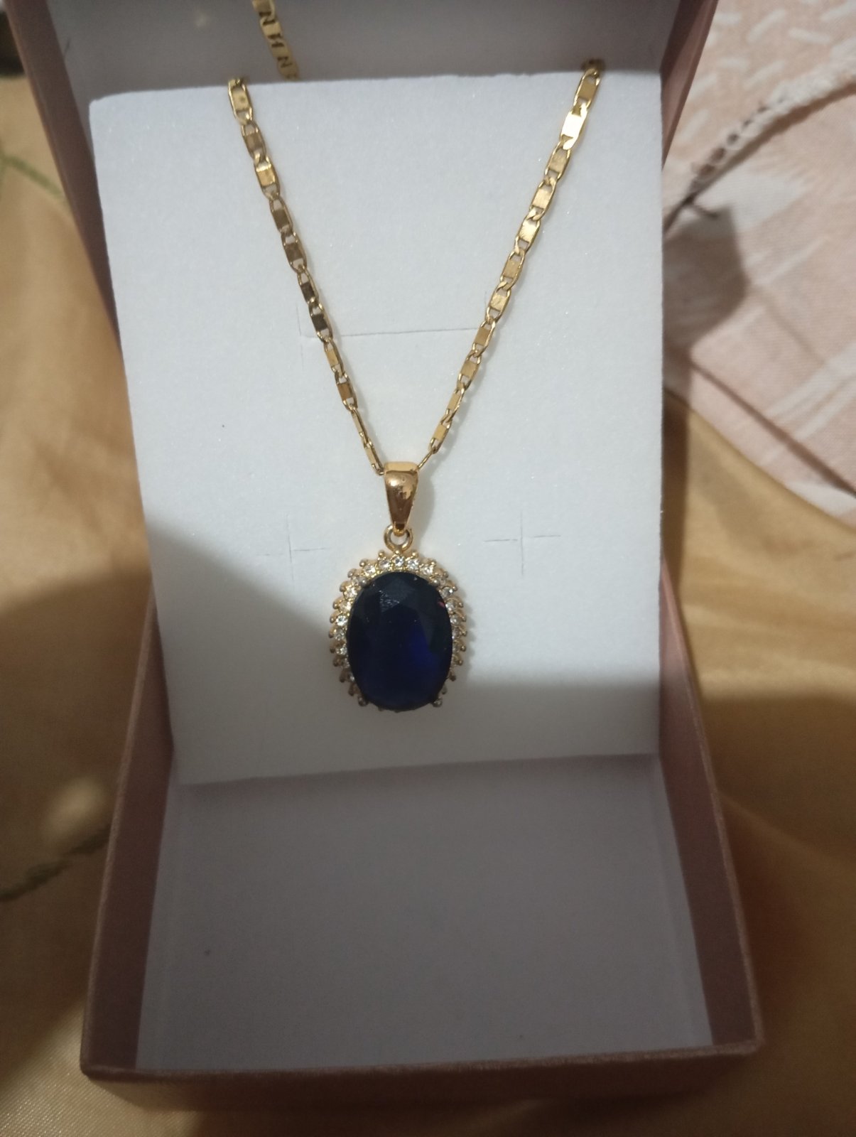 Un très jolie collier doré avec pendentif bleu