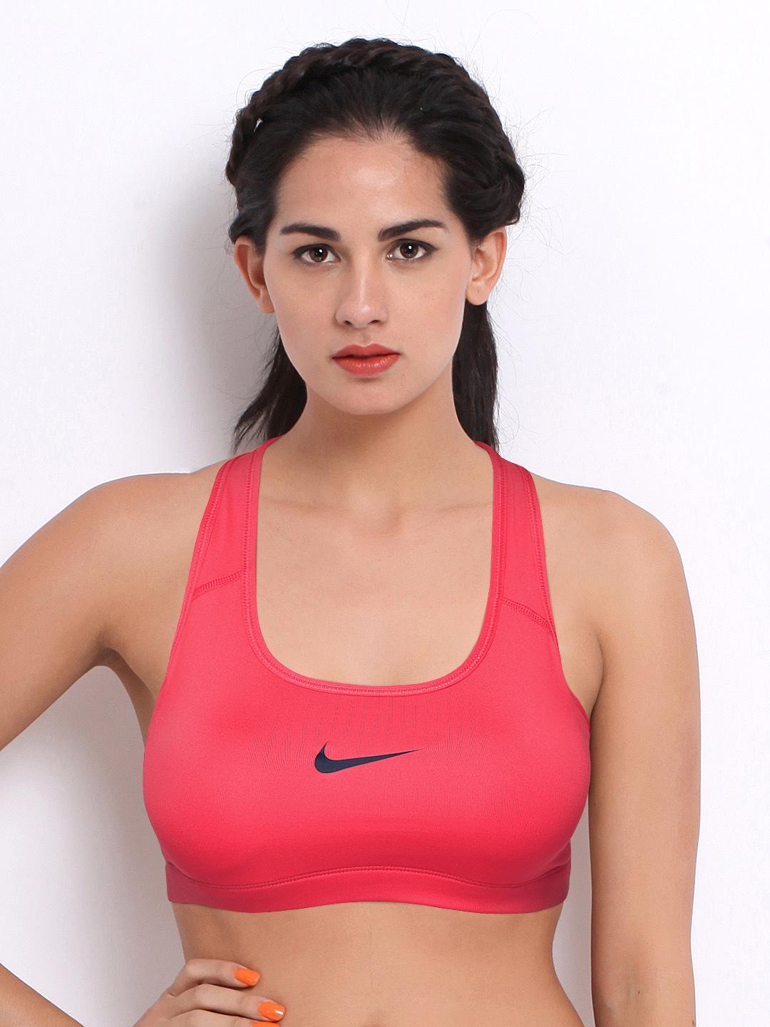 Cette brassière de sport Nike Dri-FIT présente une teinte rose néon ou corail vif. Elle arbore un col dégagé classique, une coupe ajustée et le logo emblématique Swoosh noir imprimé sur la poitrine gauche