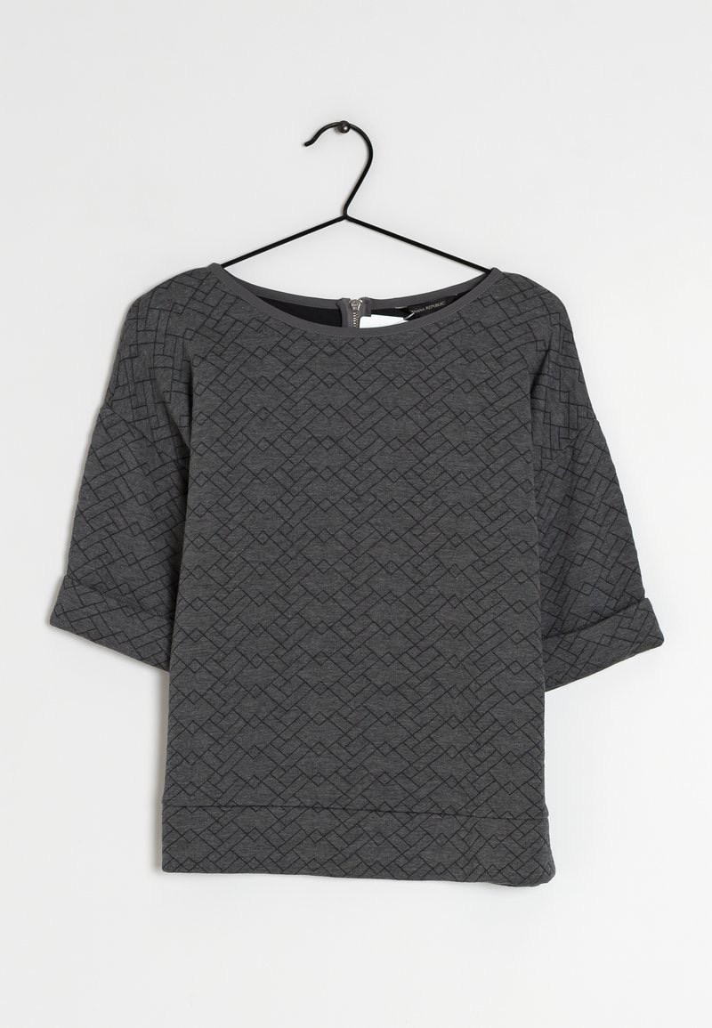 Un pull ou un t-shirt ample pour femme à manches mi-longues, de couleur gris anthracite, confectionné dans une maille matelassée à motif géométrique en relief