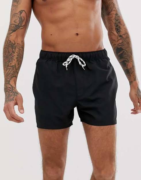Est un short de bain uni avec cordons noir de la marque Kiabi.