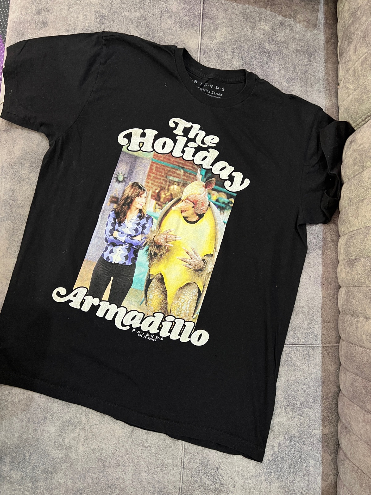 T-shirt noir est un produit dérivé officiel de la série Friends, représentant le célèbre personnage de "The Holiday Armadillo