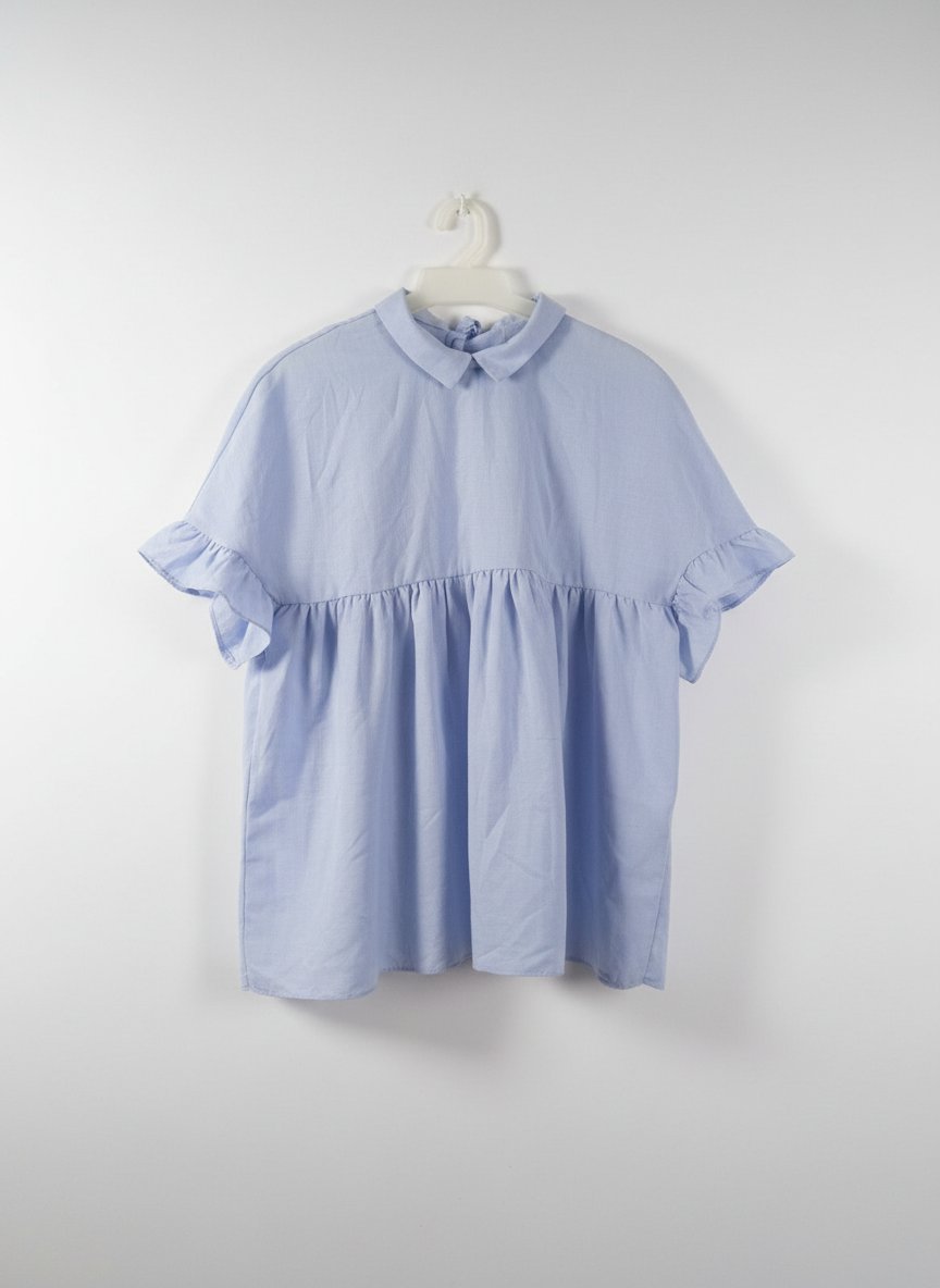  Cette blouse bleue 🩵🩵 à manches courtes présente une coupe ample avec des volants et un col plat.
