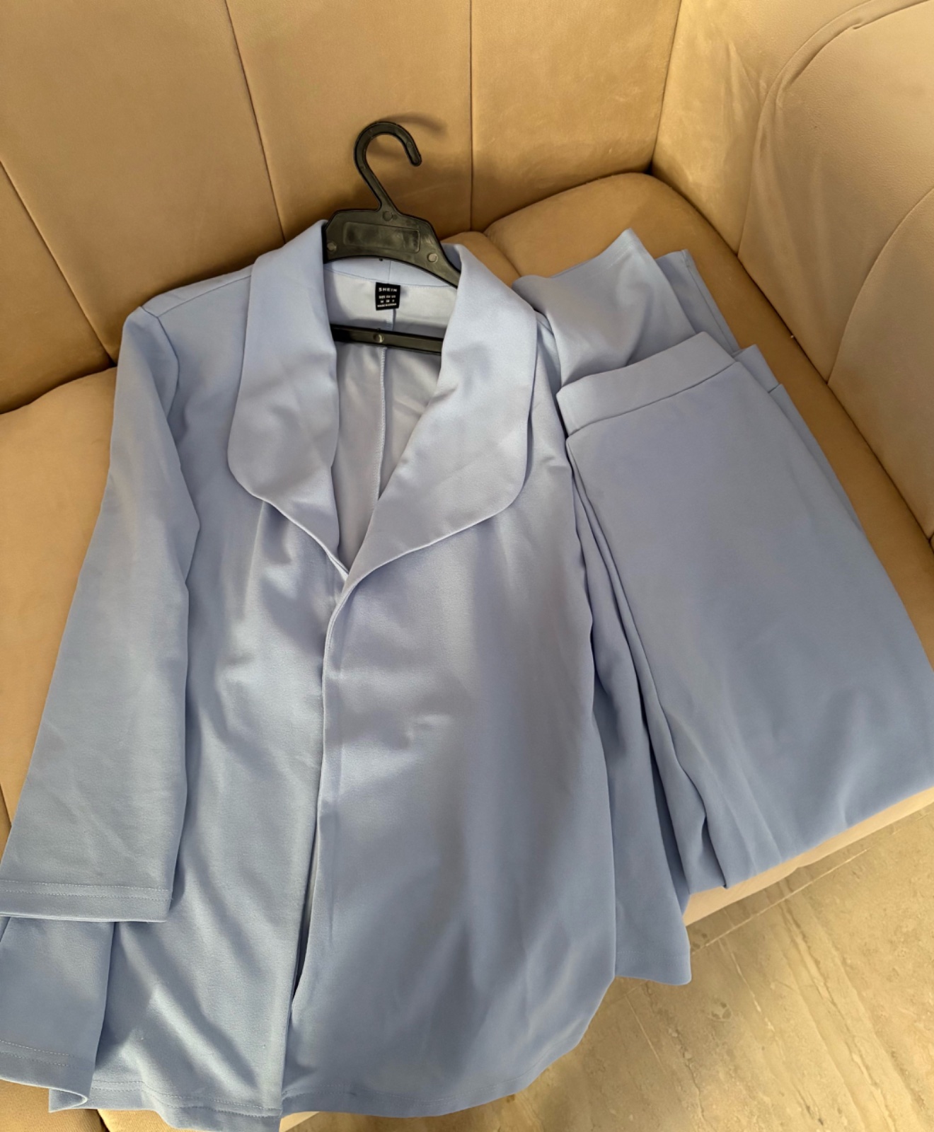 Ensemble est un tailleur deux pièces bleu ciel composé d'une veste blazer et d'un pantalon