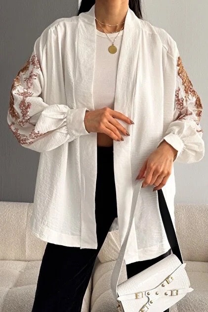 Cette chemise fluide de style kimono blanche est ornée de broderies dorées et de sequins sur les manches
