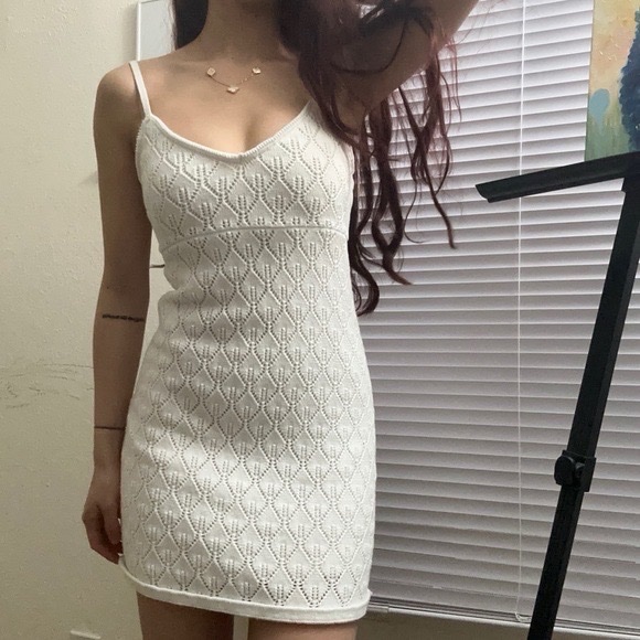 Une robe courte blanche en crochet avec des bretelles spaghetti blanche taille s