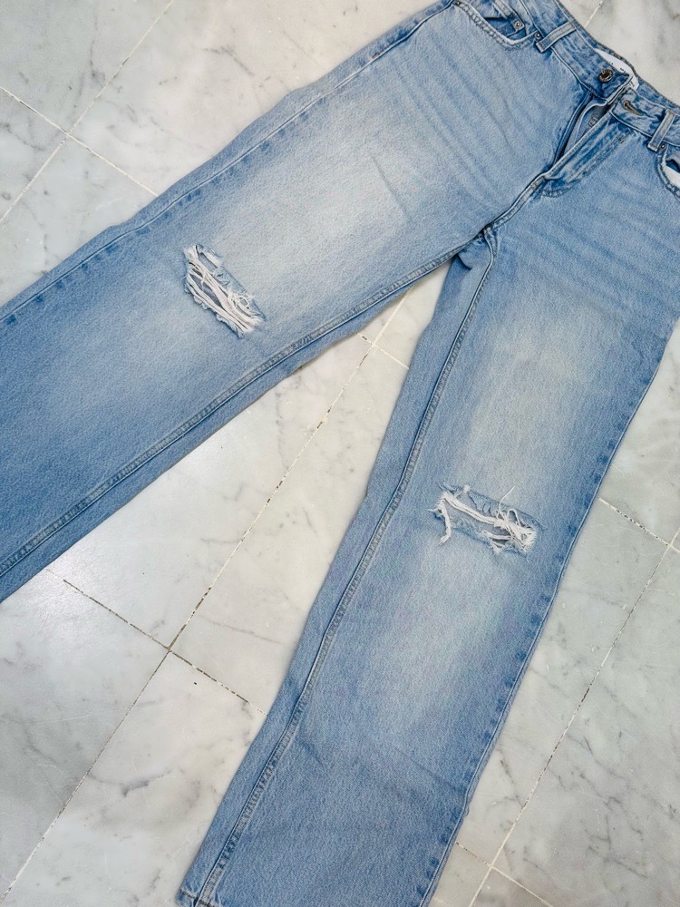 Pantalon jean bleu déchirés au niveau des genoux