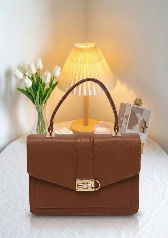 Un sac marron à la silhouette structurée et aux finitions dorées, alliant sobriété et élégance intemporelle