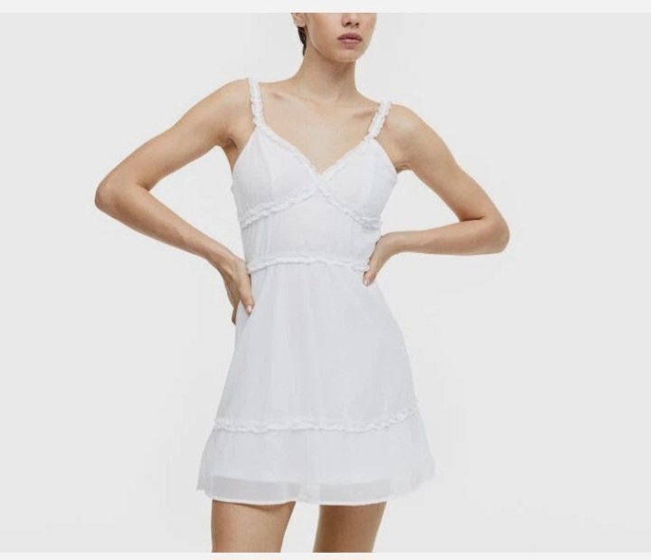 Ce crop top blanc de H&M se distingue par ses bretelles volantées et son élégant lien à nouer dans le dos