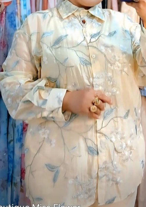  une chemise fluide jaune pâle à imprimé floral assortie d'un pantalon ample beige,