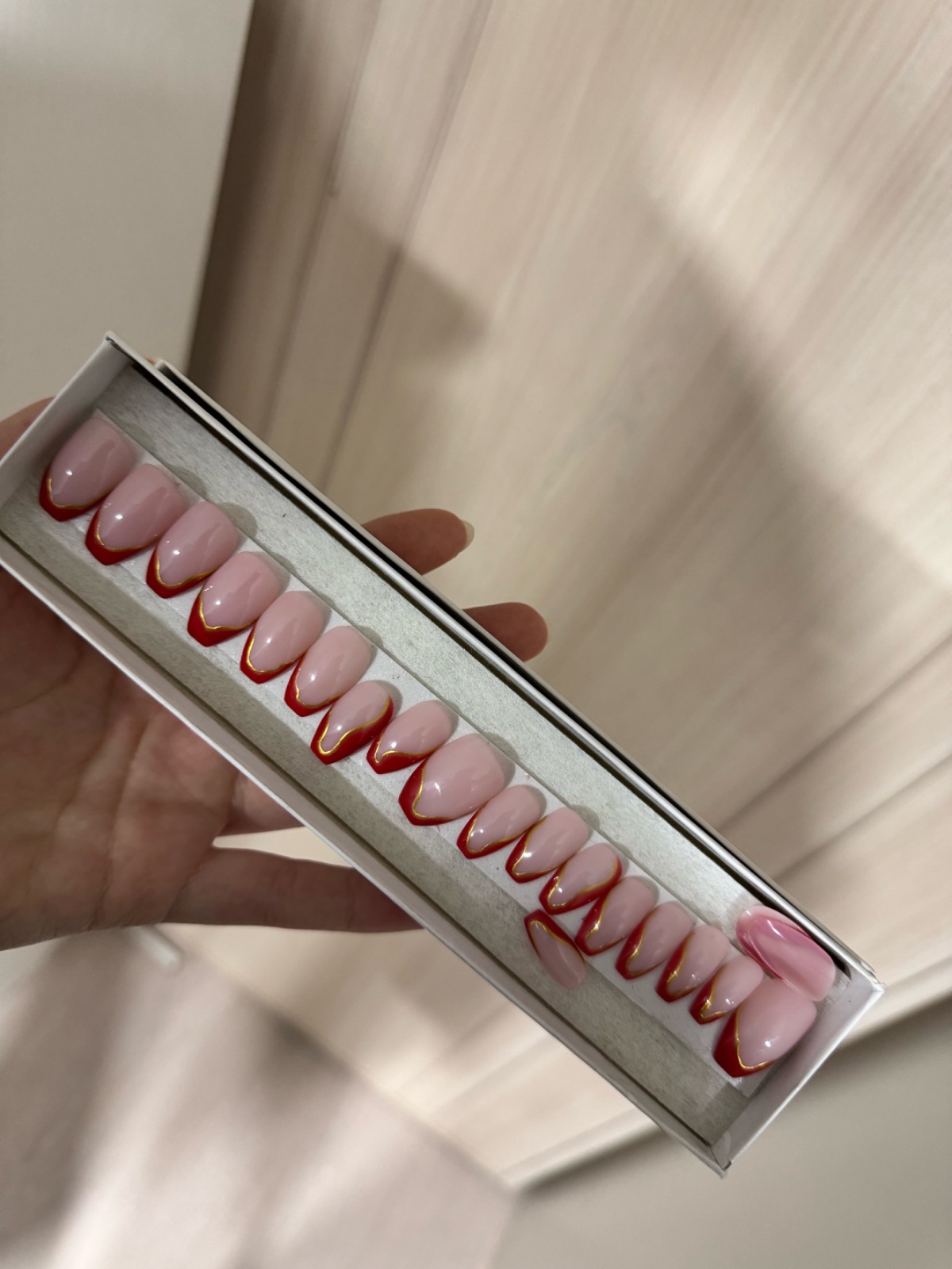 Faux ongles nude avec French rouge et liseré doré