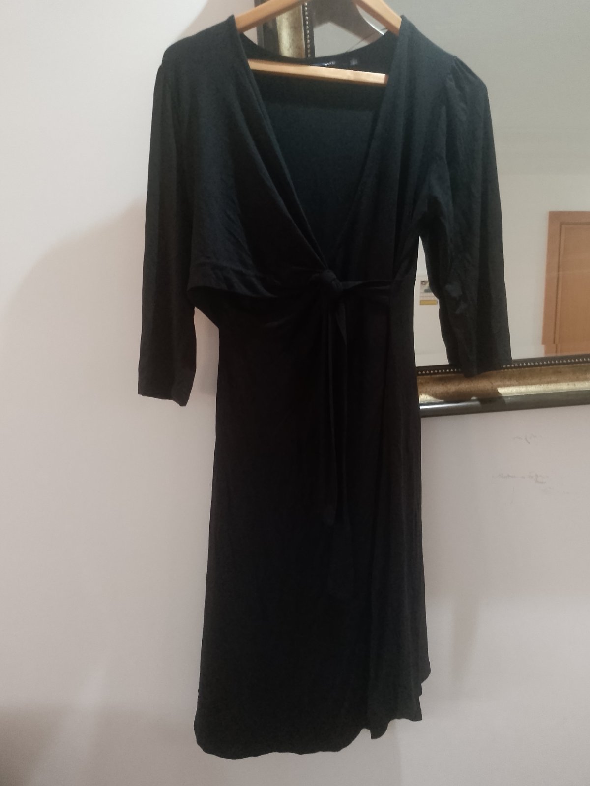 Robe cache-cœur noire de la marque Kiabi, un modèle classique à manches 3/4. Ce type de coupe fluide avec un nœud drapé à la taille est particulièrement populaire dans la gamme de maternité et d'allaitement