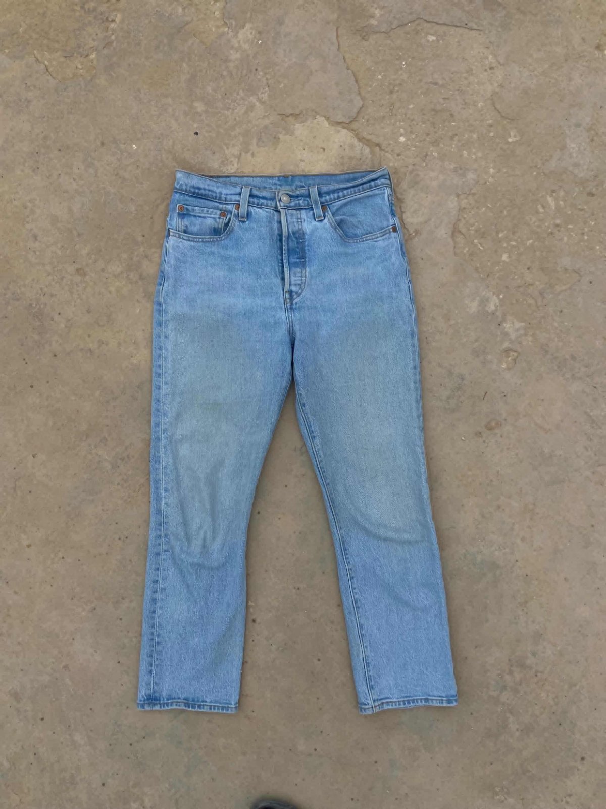 Jean semble être un modèle droit en denim de couleur bleu clair délavé de la marque Levi's 501
