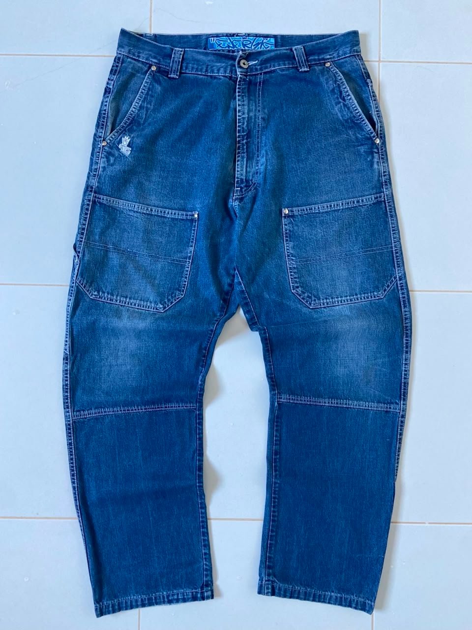 Jean de style charpentier (carpenter jeans) arbore une coupe droite décontractée et des détails utilitaires robustes inspirés du workwear